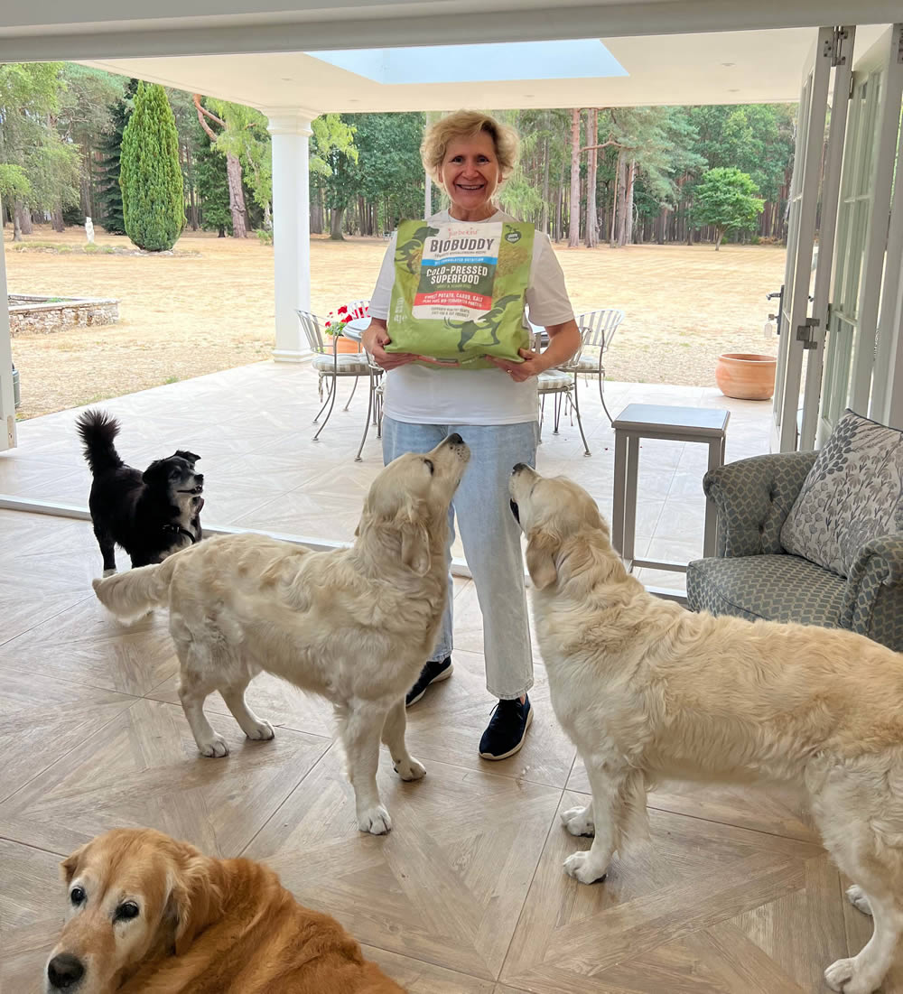 Dr Arielle and Ruff holding a bag of BioBuddy and 2 Golden Retrievers sniffing